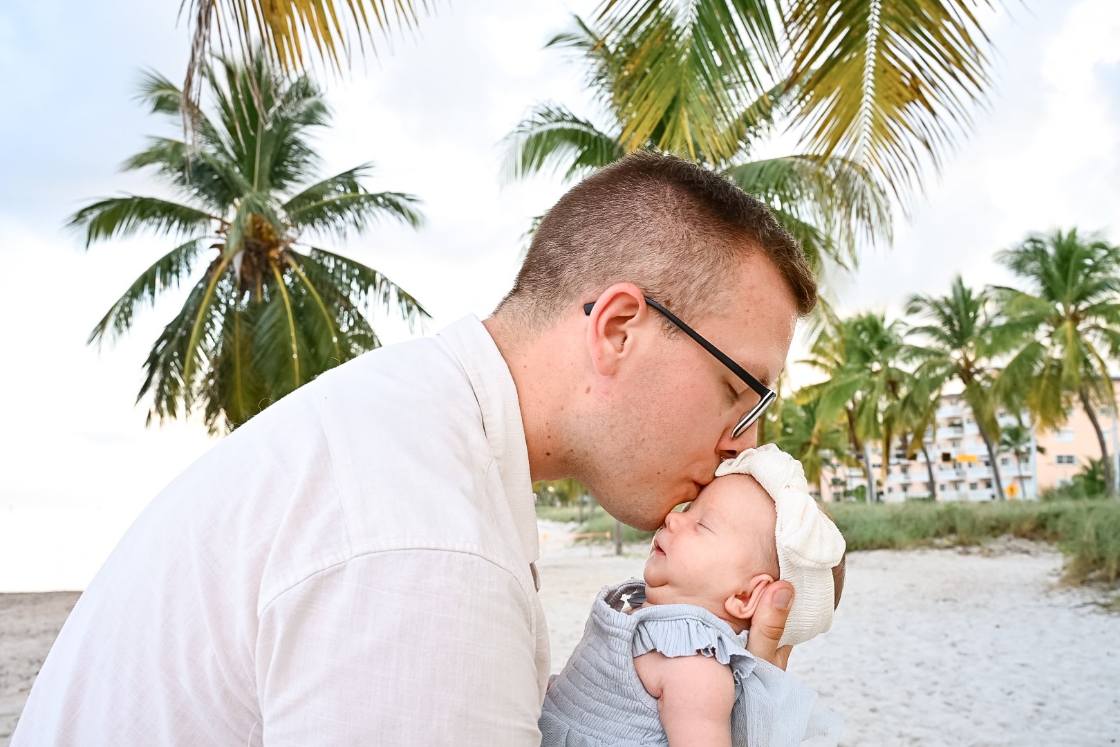 Father kissing his newborn during a beach family session